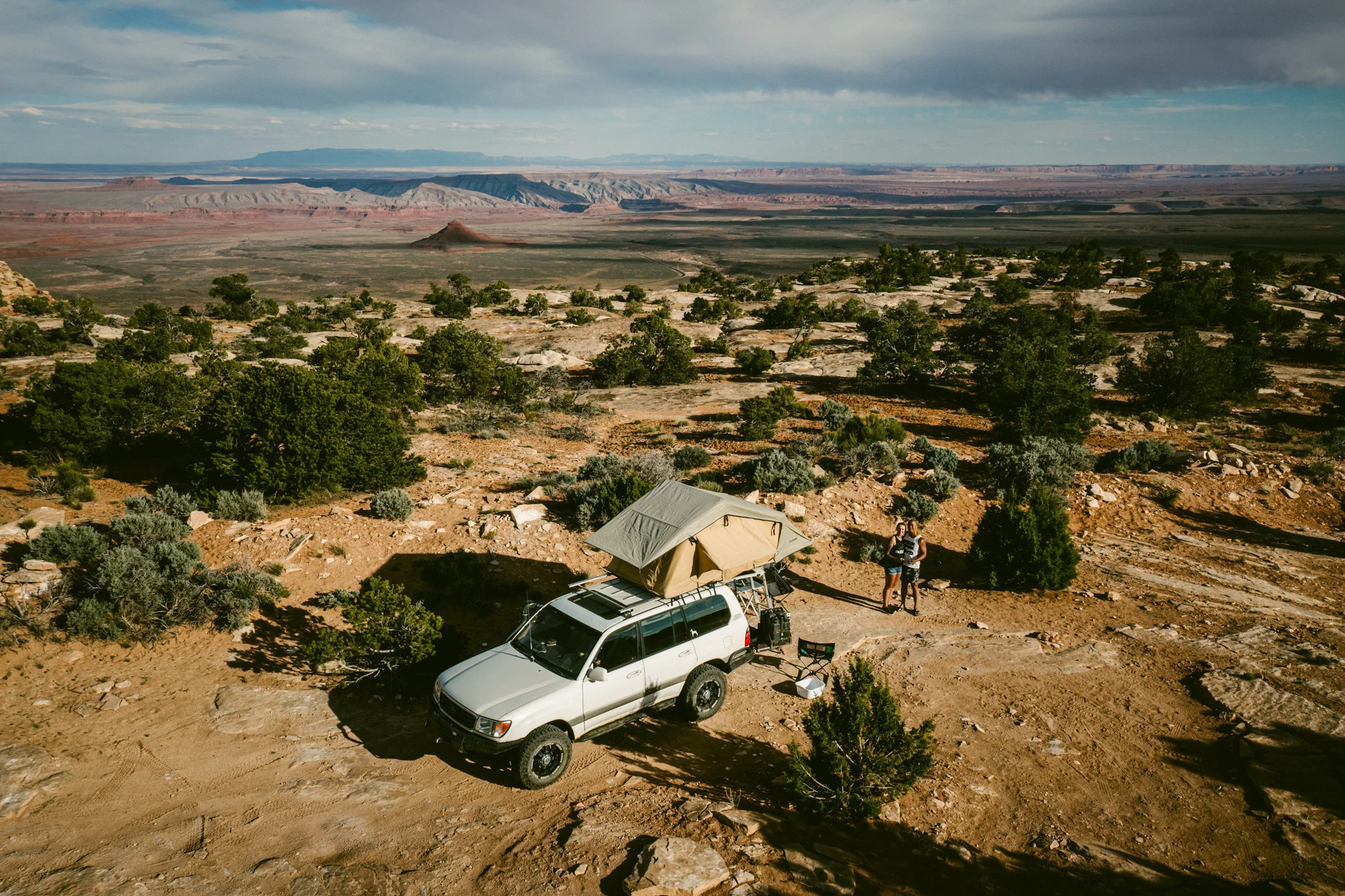 Rick and Aneta Dang seated beside their vehicle in a mountain landscape.